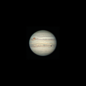 The image shows Jupiter with its cloud bands and zones. The great red spot is on the left upper side of the planet and is close to rotating around to the far side. A small sharply defined black spot is at the lower right of the planet denoting the shadow of the Jovian moon Europa.
